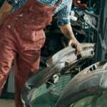 Cropped view of repairman choosing spare parts on car junkyard.